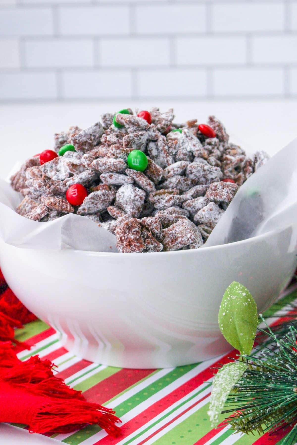 white bowl filled with christmas muddy buddies and topped with red and green M&M's