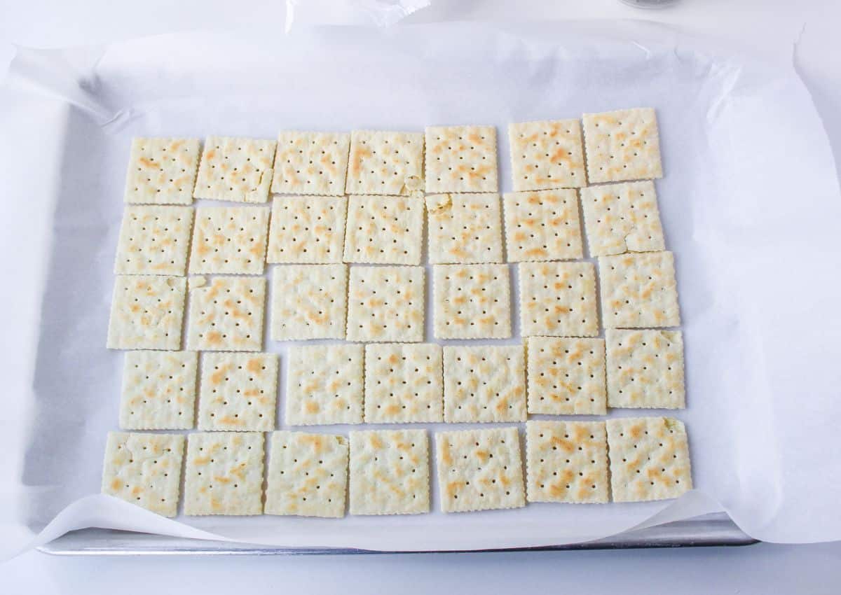 saltine crackers on a parchment lined baking sheet