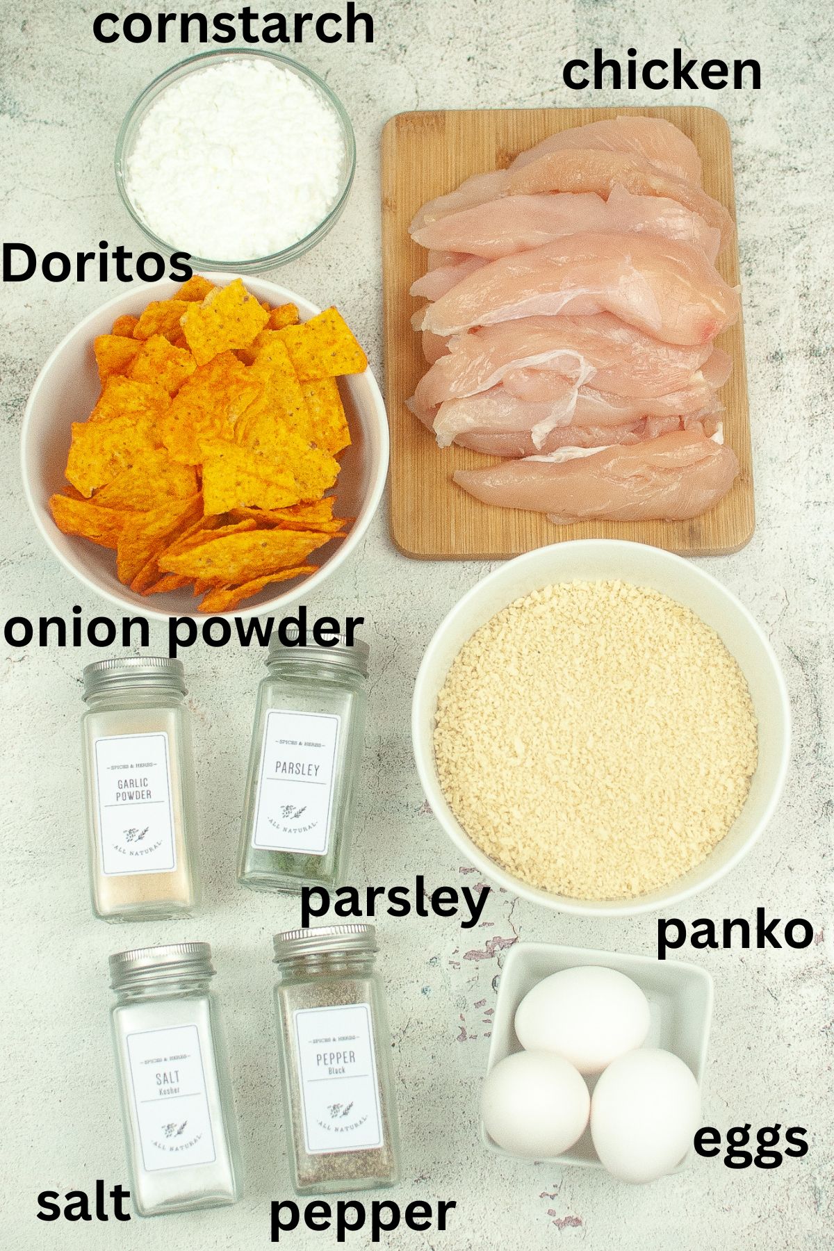 cornstarch, chicken tenders, dortios, onion powder, parsley, panko, eggs, salt, pepper on a textured background