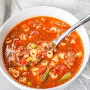 close up image of a white bowl filled with busy day soup with a spoon in it