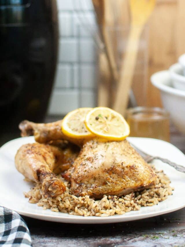 chicken quarters on a on bed of rice pilaf on a white plate