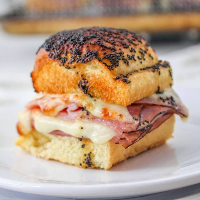ham and cheese slider on a white plate with more in the background