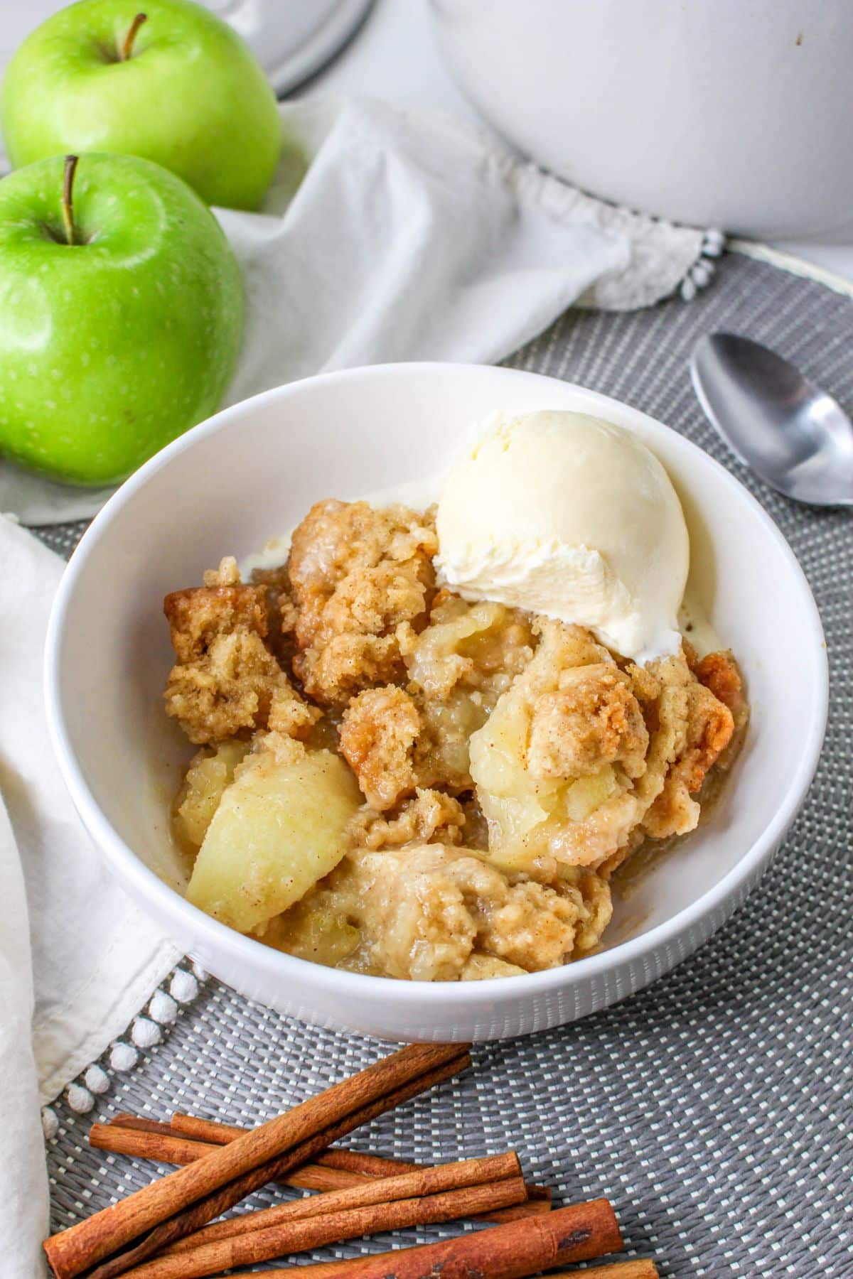 white bowl filled with apple cobbler and topped with a scoop of vanilla ice cream
