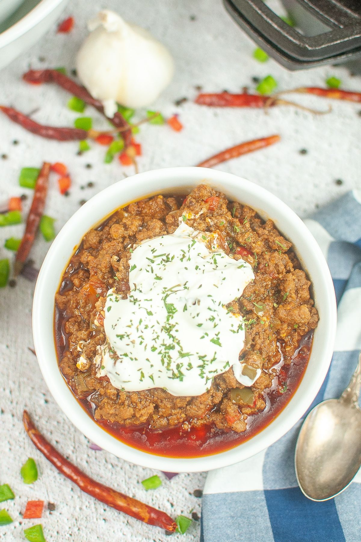 birds eye image of a bowl of chili topped with sour cream and parsley