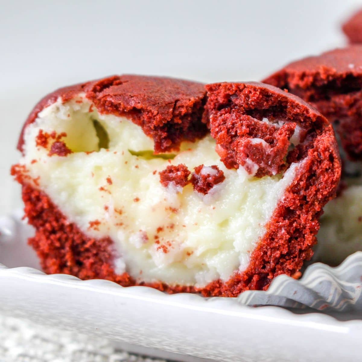 close up of one half of a red velvet muffin split open to show the cream cheese filling on the inside