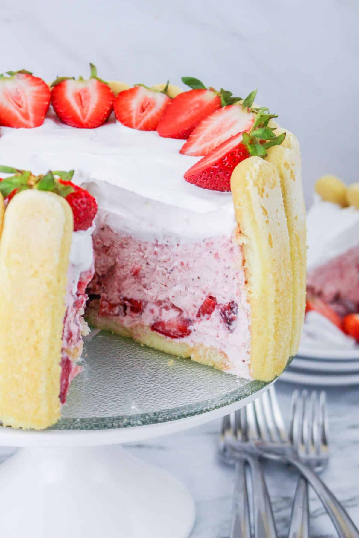 close up of a strawberry charlotte cake with a slice missing