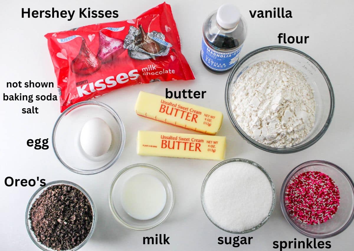 Hershey Kisses, vanilla, flour, butter, egg, Oreos, milk, sugar, and sprinkles on a white background