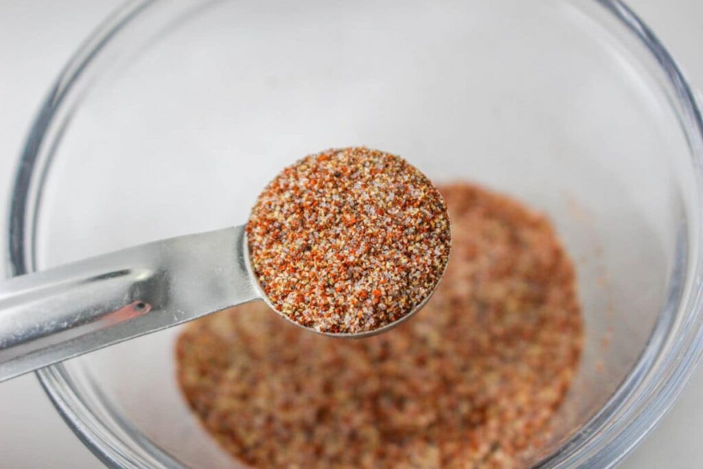 garlic powder, salt, pepper, and smoked paprika mixed together in a measuring spoon in the air