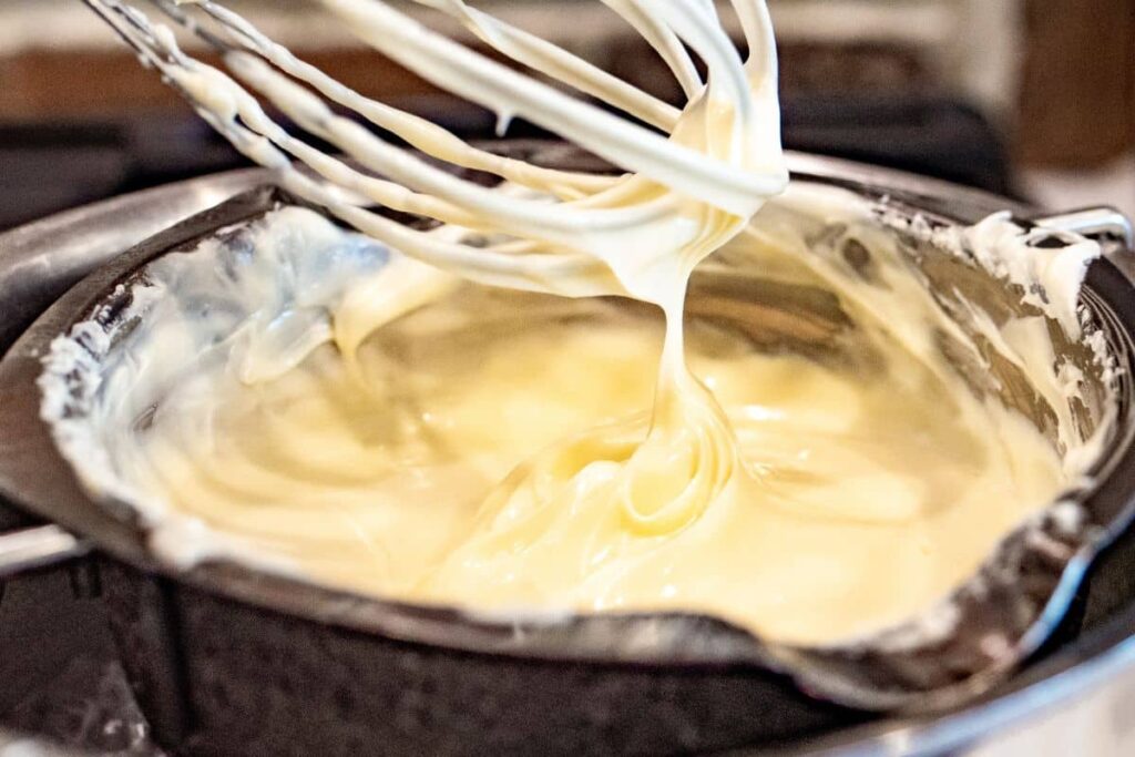 white chocolate being stirred with a wire whisk and melted in a double boiler