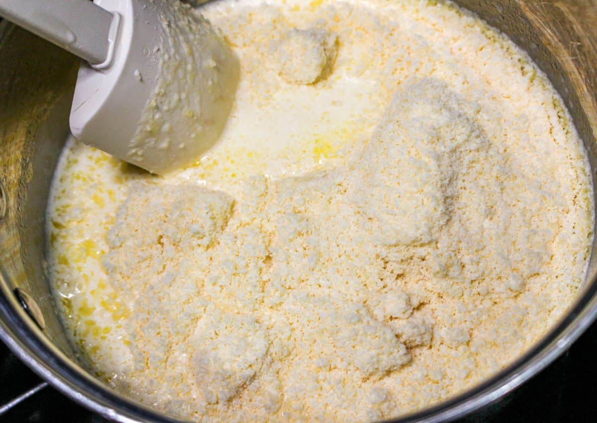 parmesan cheese being added to heavy cream and melted butter