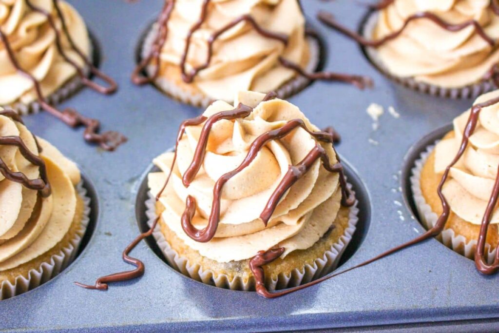 chocolate being drizzled on top of the cupcakes