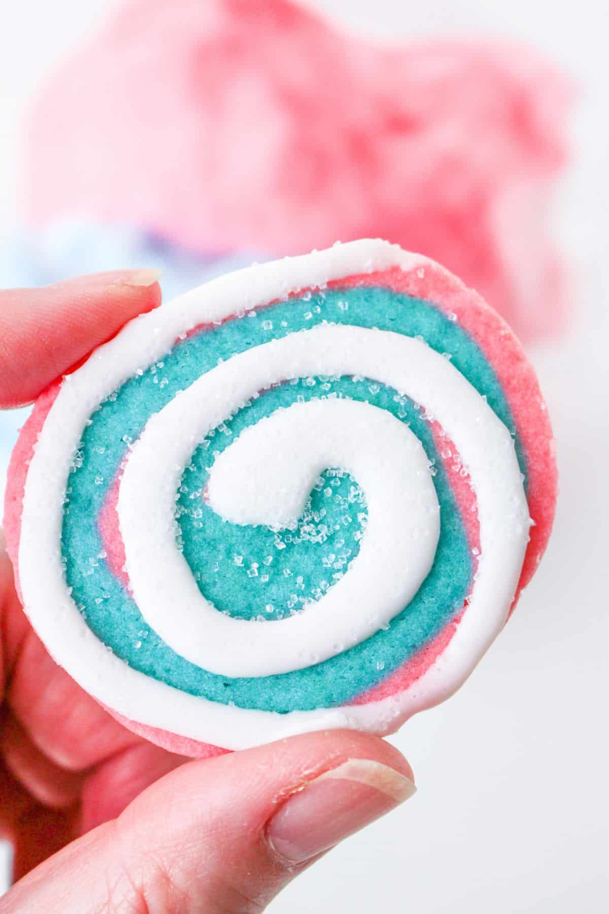 cotton candy cookie held in the air in a woman's hand