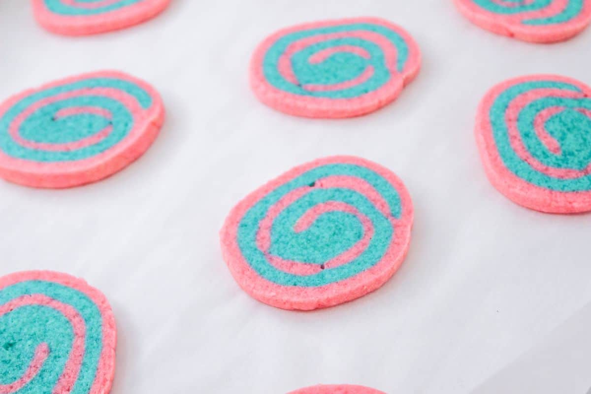baked pink and blue swirled cookies on a parchment lined baking sheet