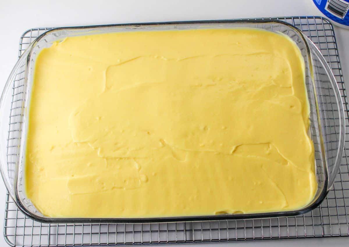 vanilla pudding being spread over a glass baking dish