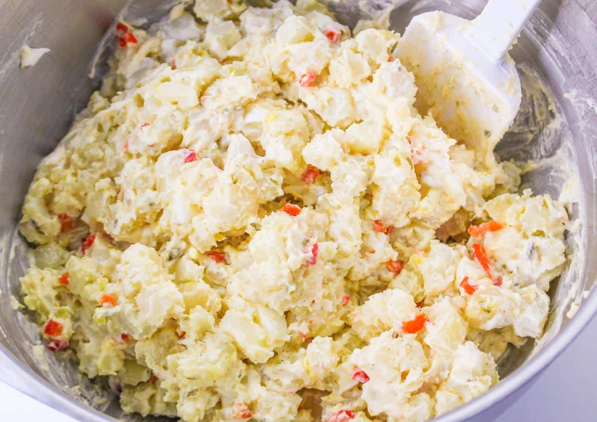potato salad mixed together in a stainless steel mixing bowl