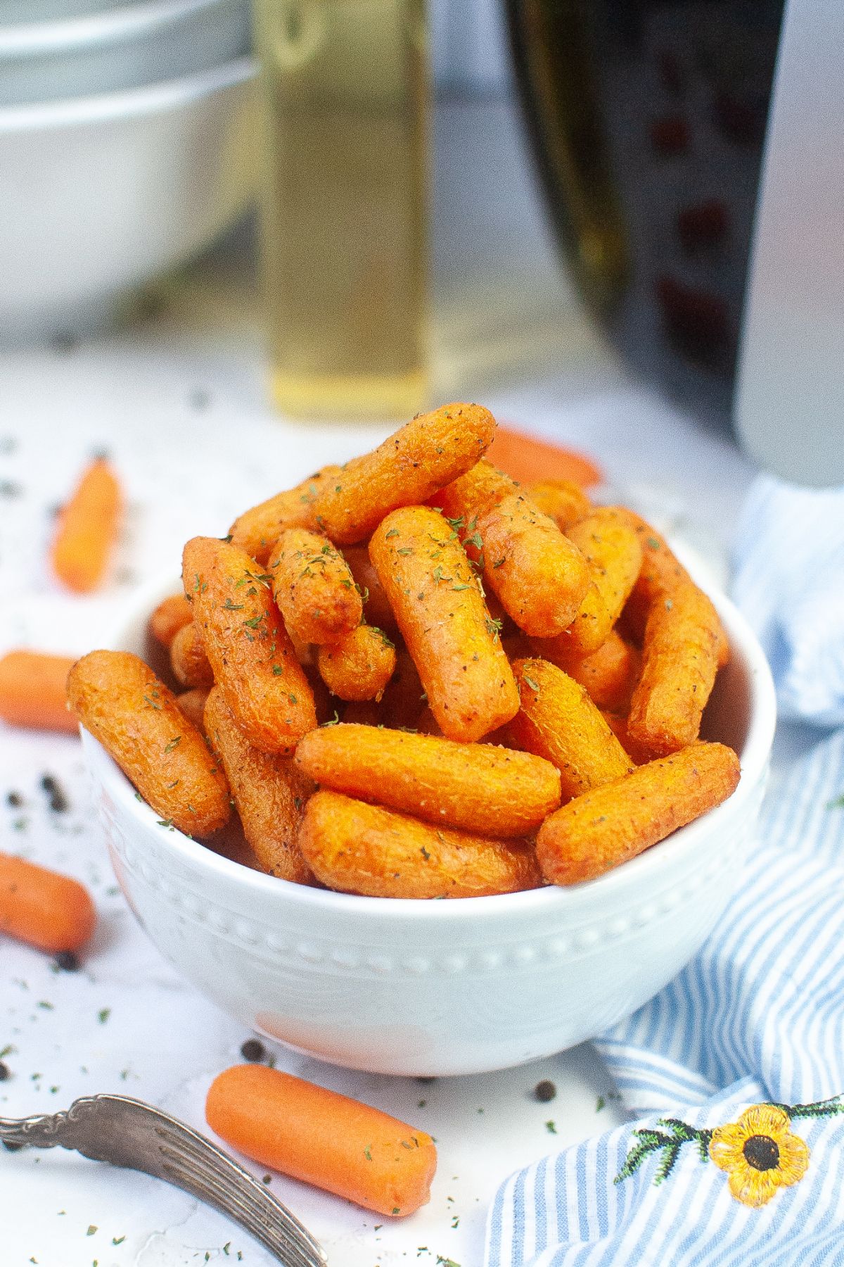 white bowl filled with air fryer baby carrots with a air fryer in the background