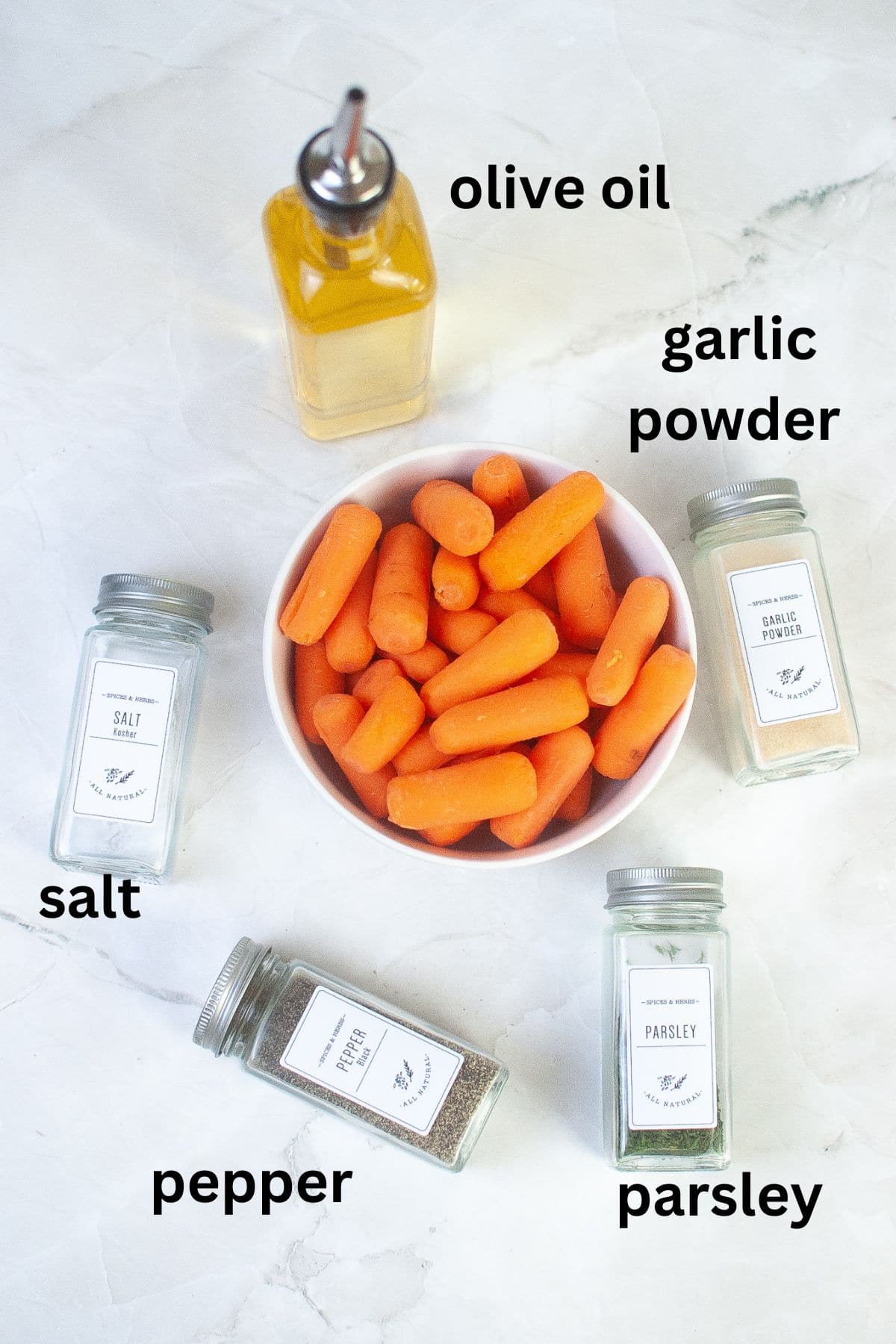 bottles of olive oil, salt, pepper, parsley, garlic powder, and a white bowl filled with raw carrots