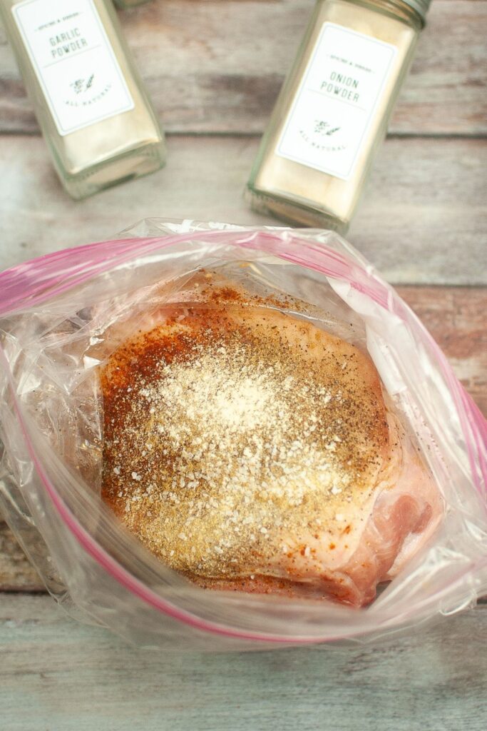 pork butt being marinaded in a storage bag with seasonings and olive oil