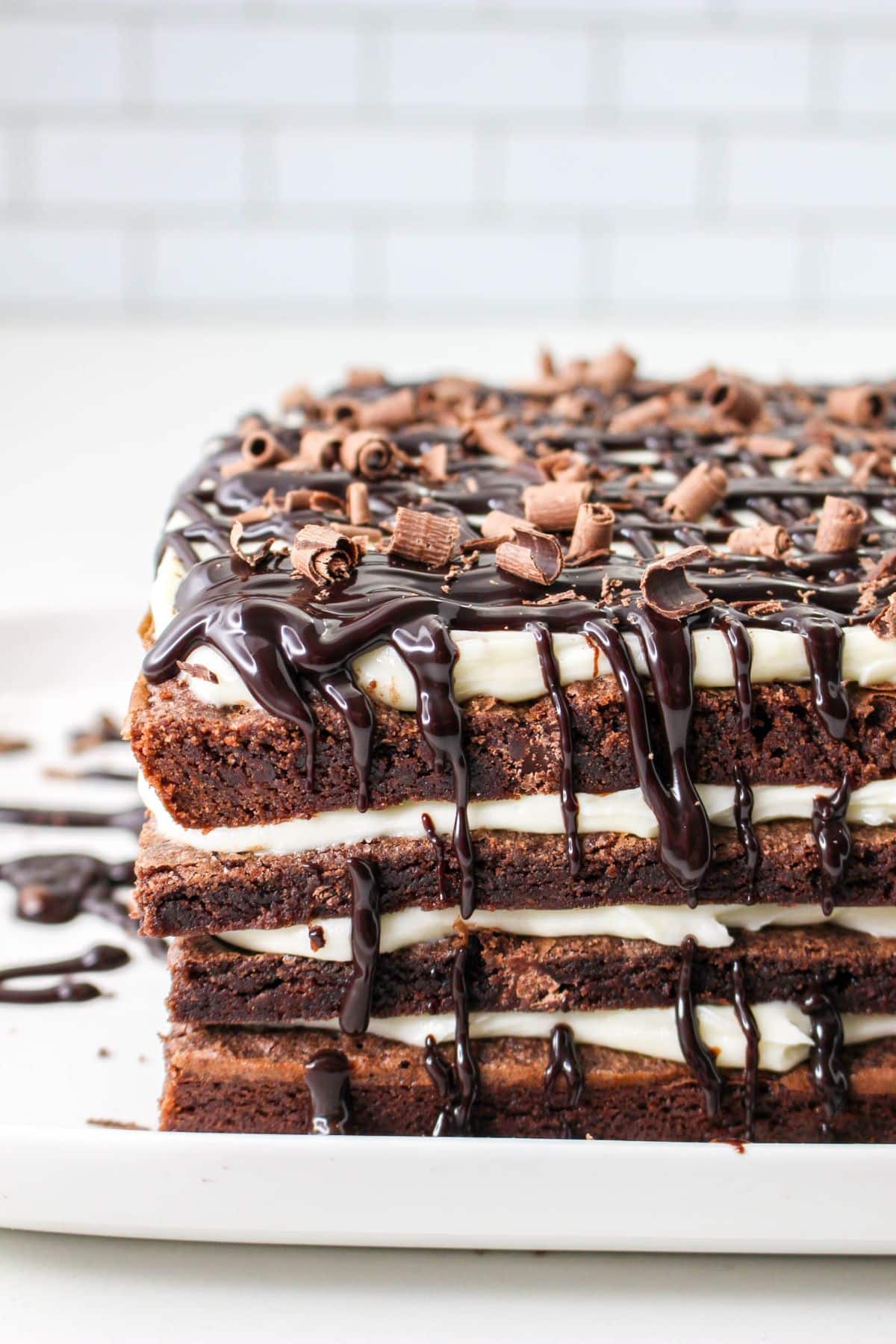 off center image of brownie lasagna topped with chocolate curls on a white plate