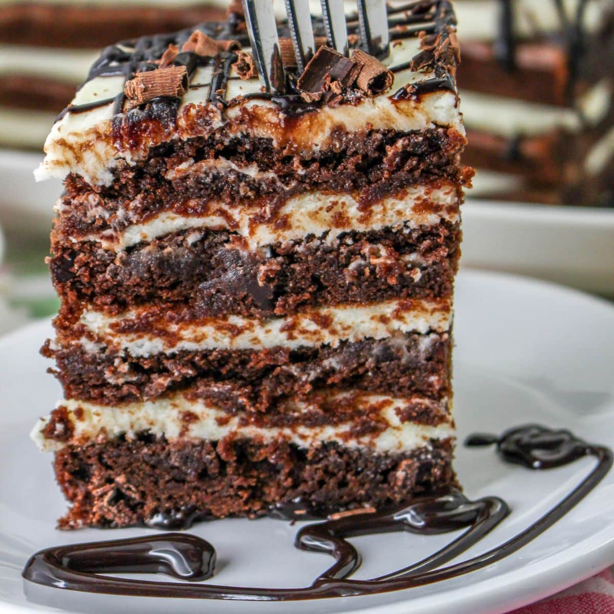 slice of brownie lasagna on a white plate with a sliver fork removing a bite