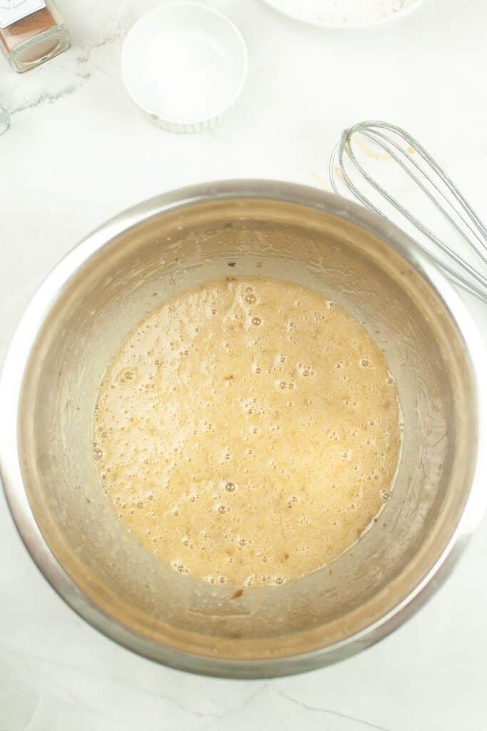 wet ingredients being whisked in a stainless steel mixing bowl
