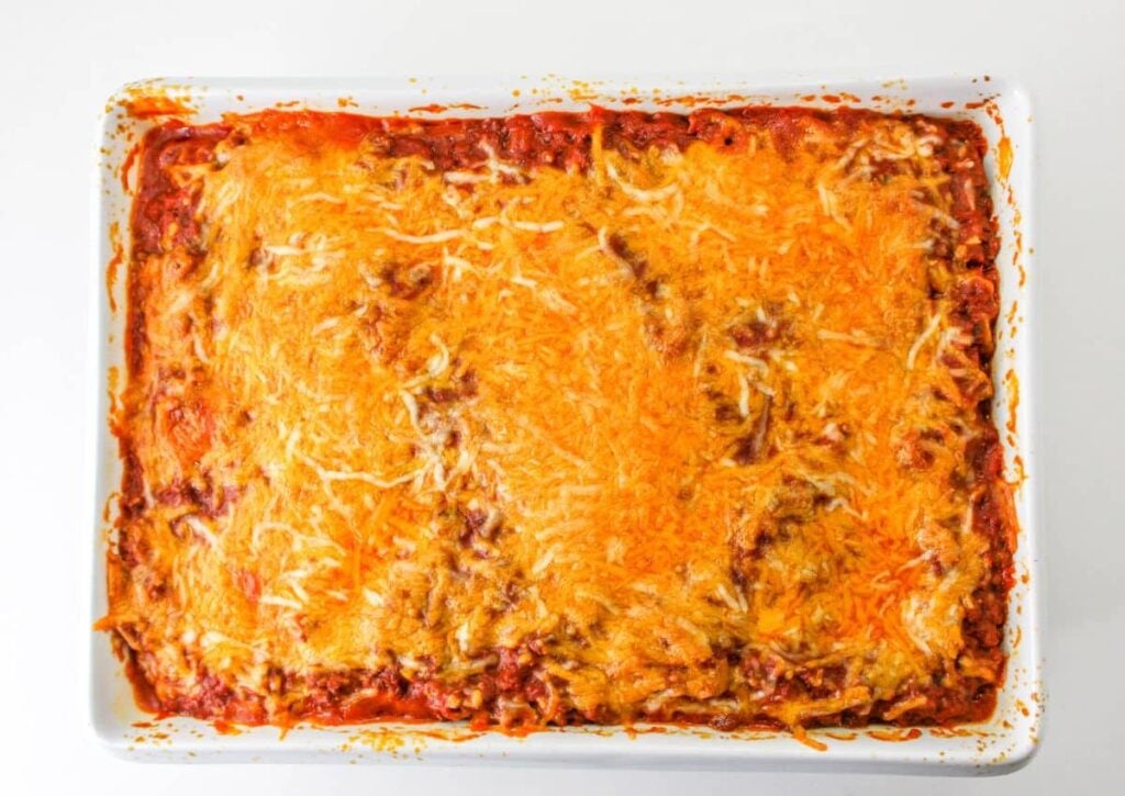 baked casserole topped with shredded cheese in a white baking dish