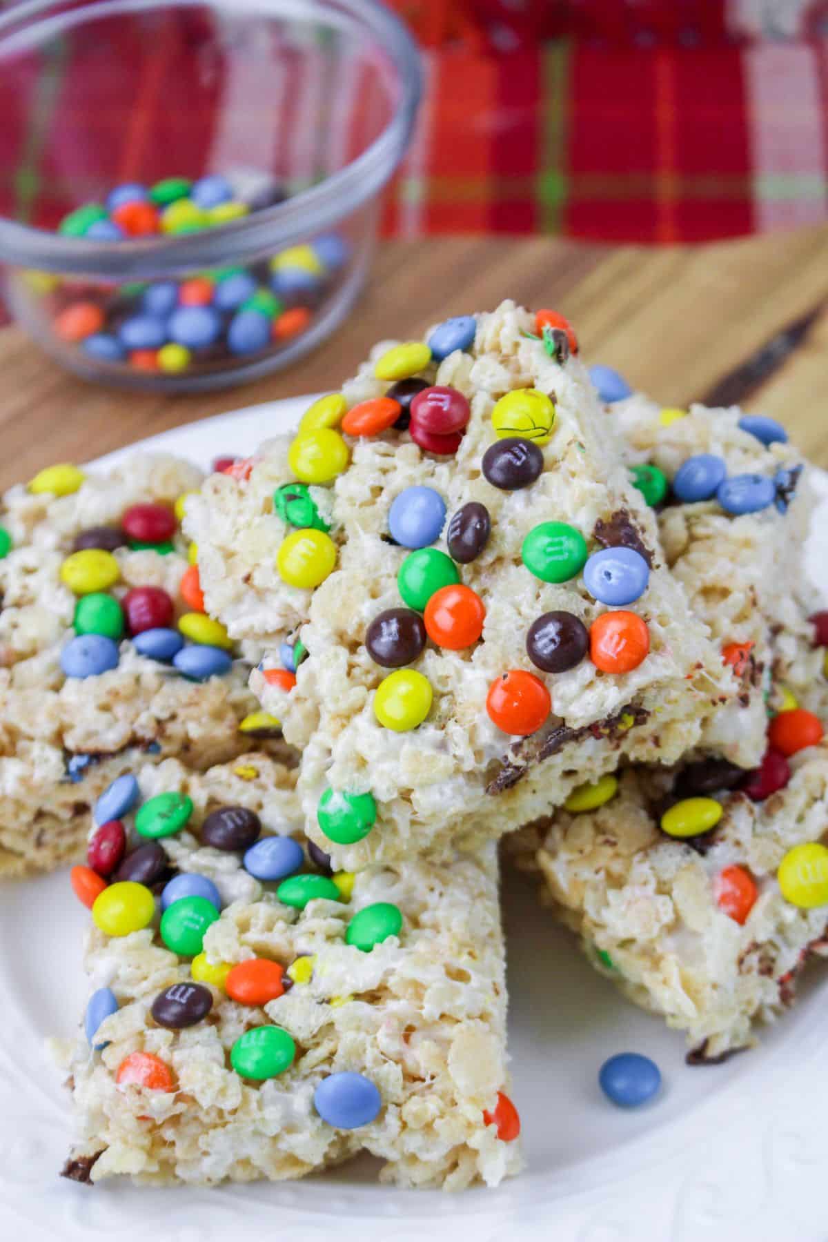 five m&m rice krisipes treats stacked on a white plate with m&ms sprinkled around