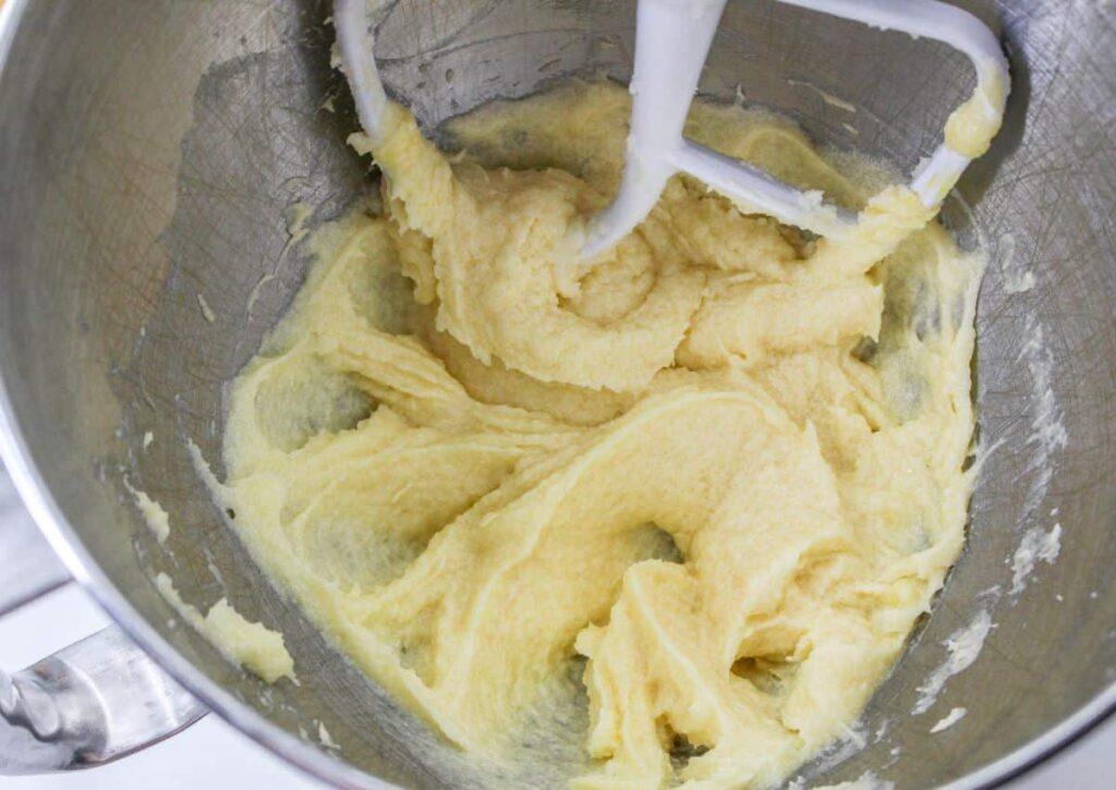 butter and sugar being creamed in the bowl of a stand mixer
