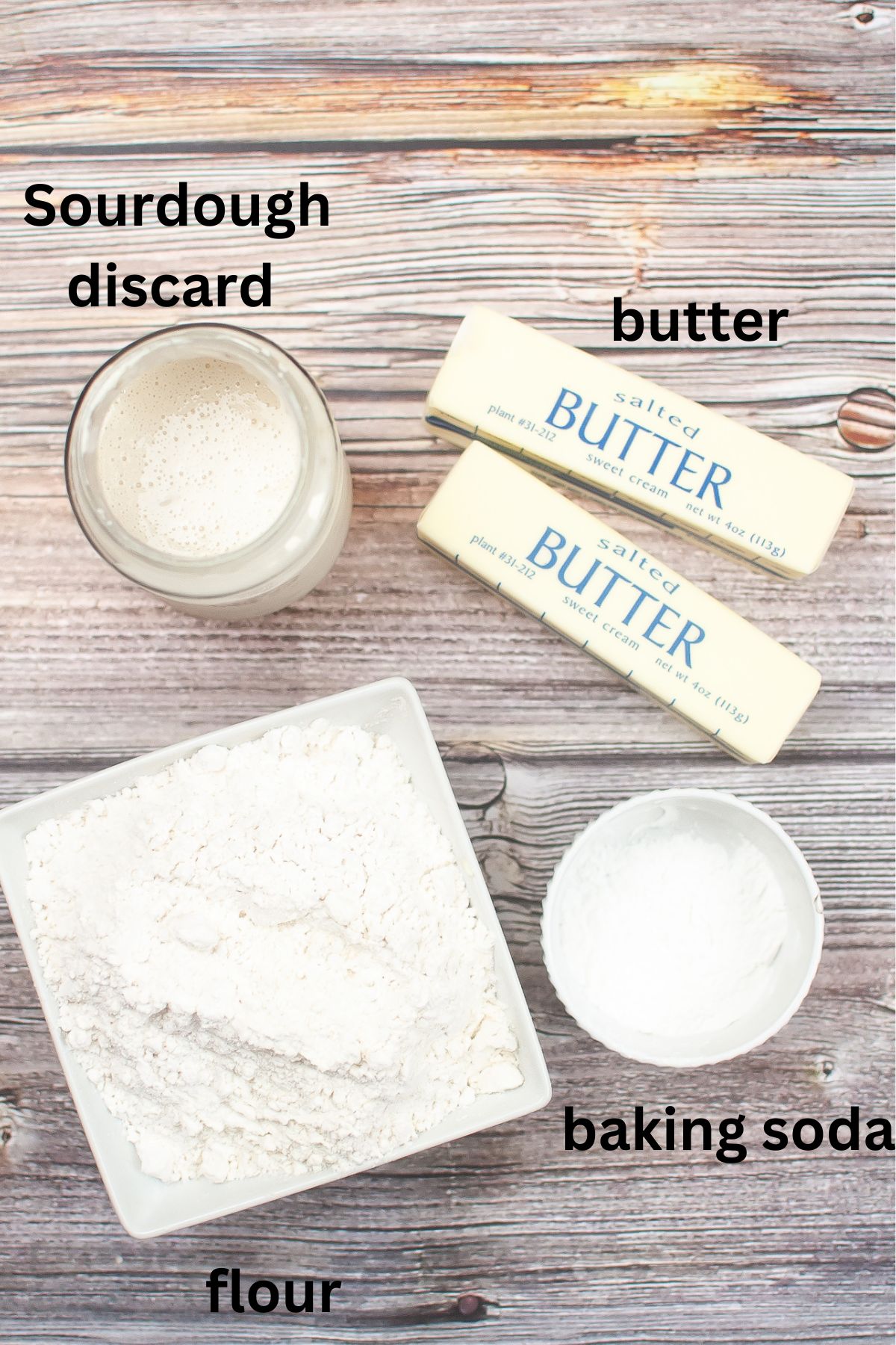 bowls of sourdough discard, butter, flour, and baking soda on a wooden background