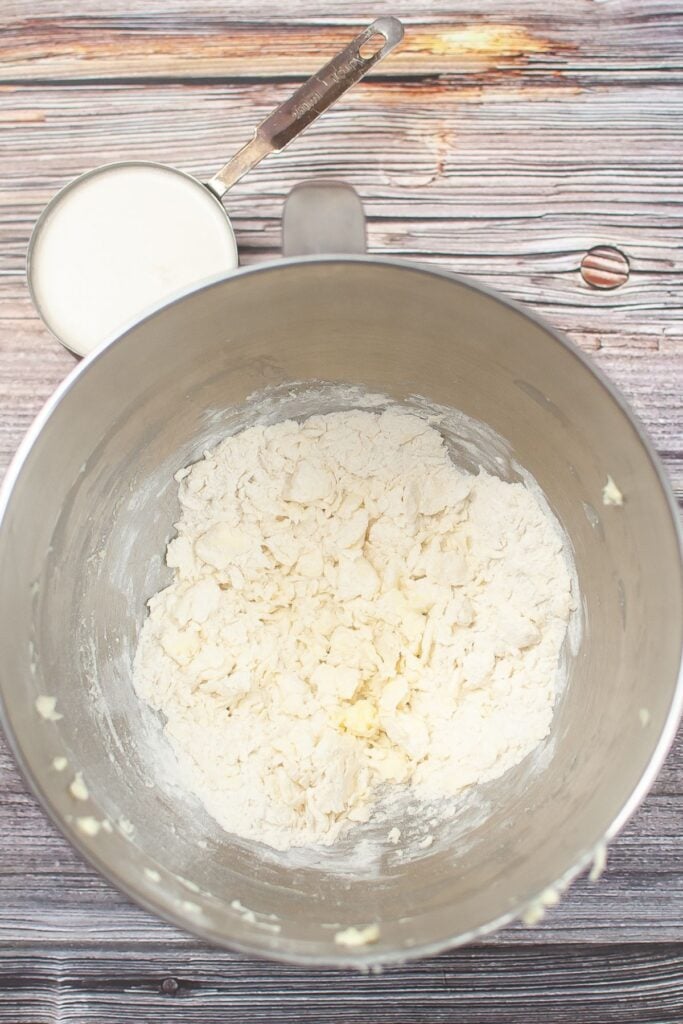 flour, baking soda, and butter being mixed in a stainless steel mixing bowl