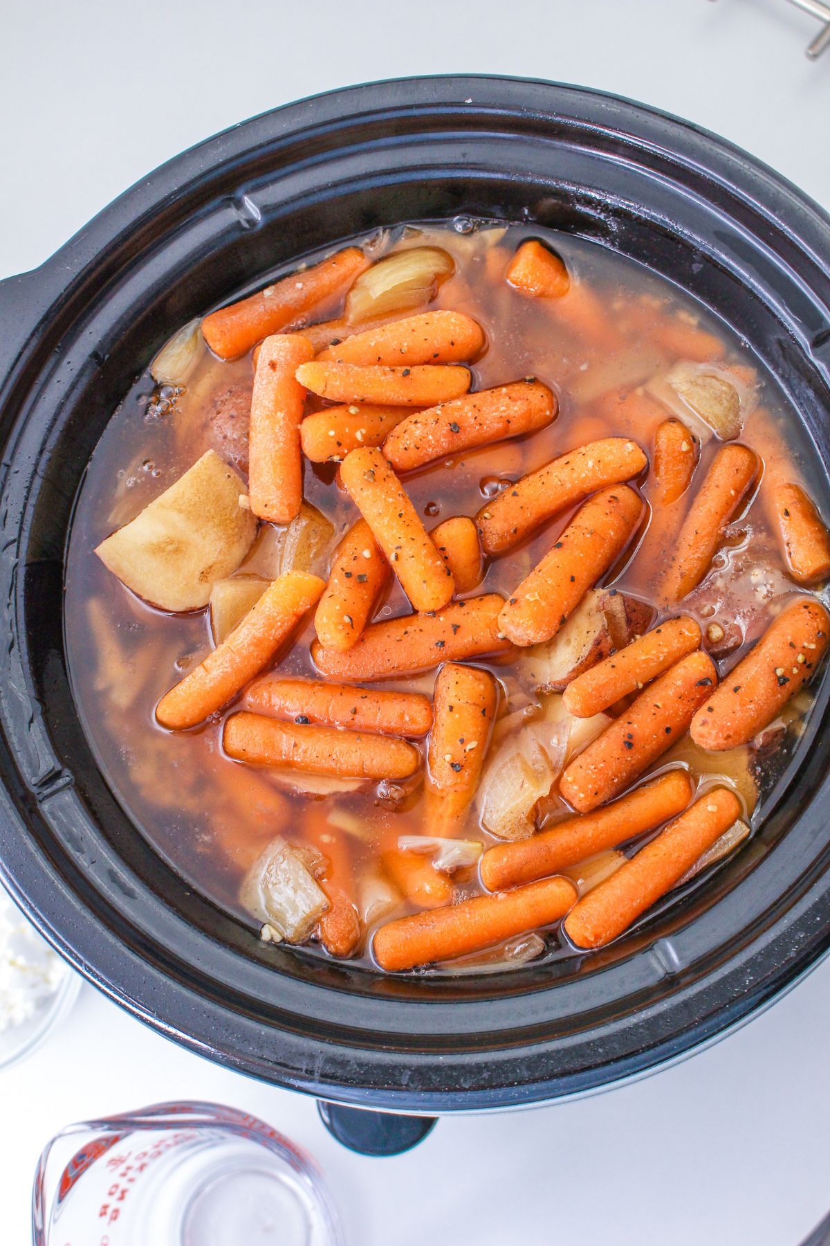 cooked pot roast, carrots, and potatoes in a slow cooker.