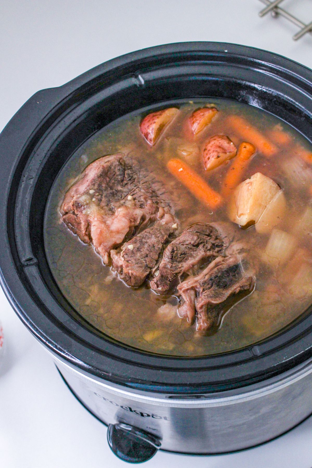 cooked pot roast, carrots, and potatoes in a slow cooker.