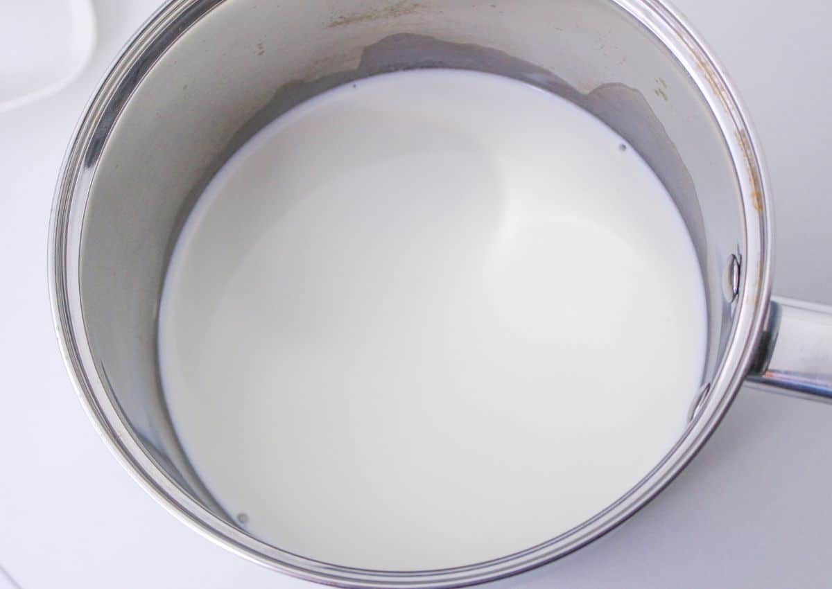 milk being heated in a stainless steel saucepan.