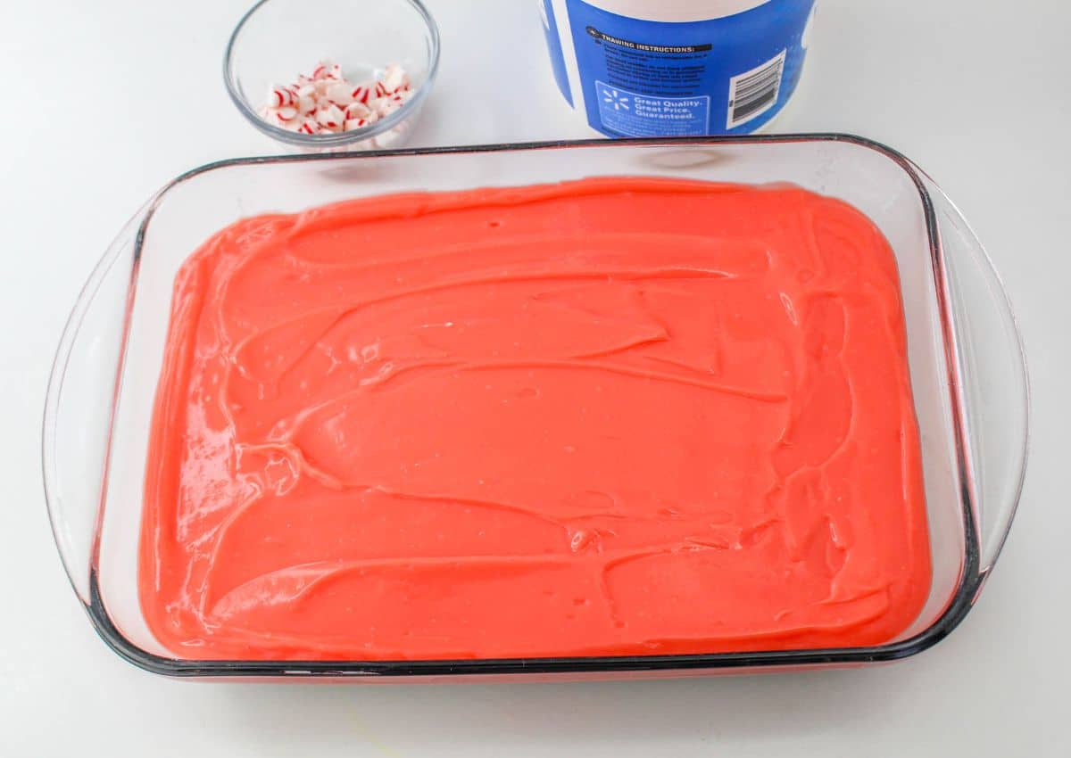 red vanilla pudding mixture being spread on top of the cream cheese layer.