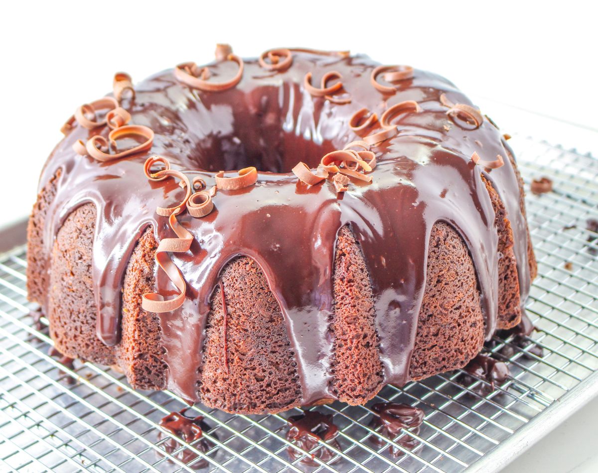 chocolate sour cream pound cake being topped with chocolate glaze and chocolate curls.