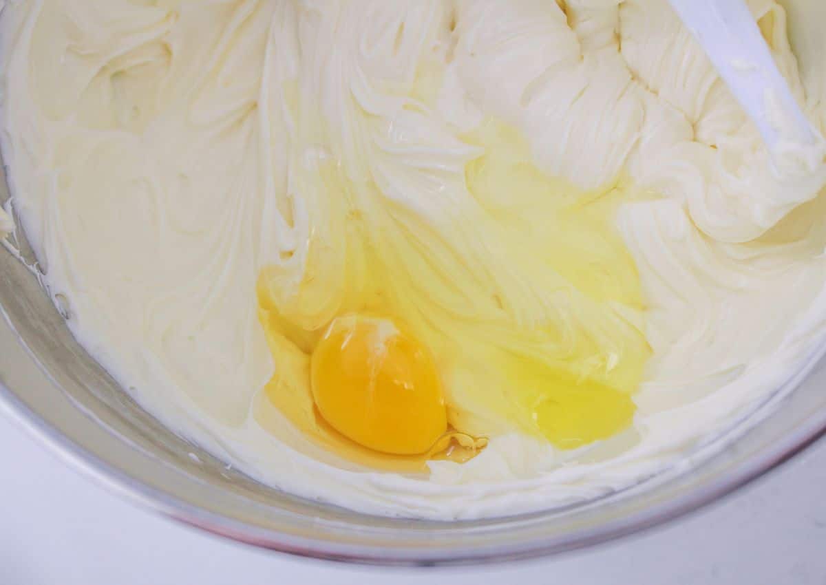 cream cheese, eggs, sugar, and vanilla being creamed in a stand mixer.