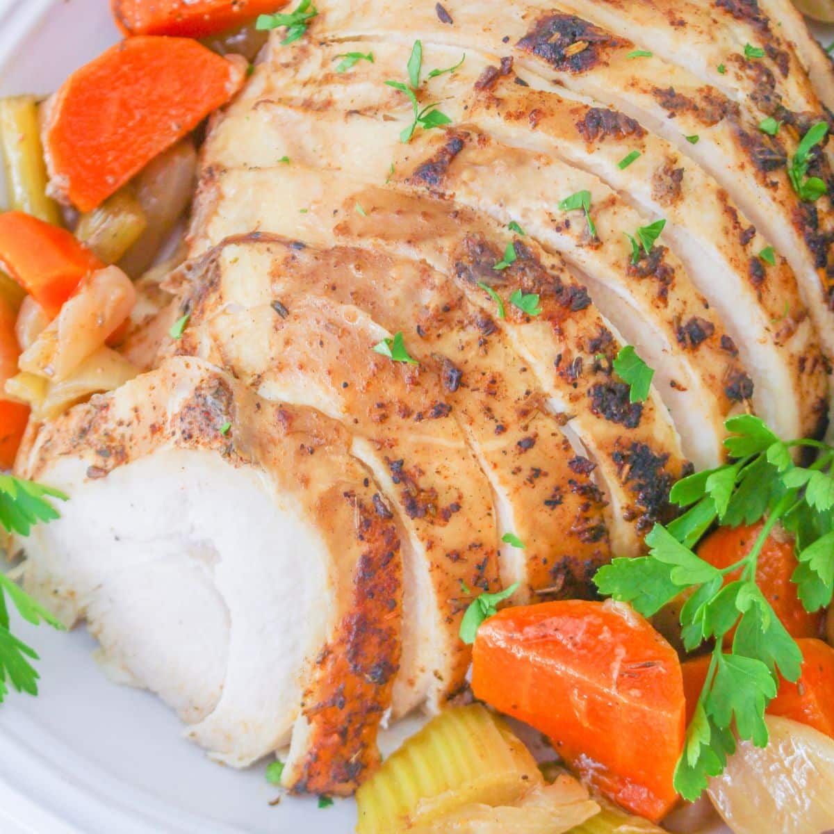 sliced turkey breast on a plate surrounded by vegetables.