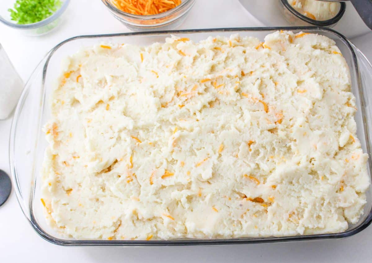 mash potatoes spread in an even layer in a casserole dish.