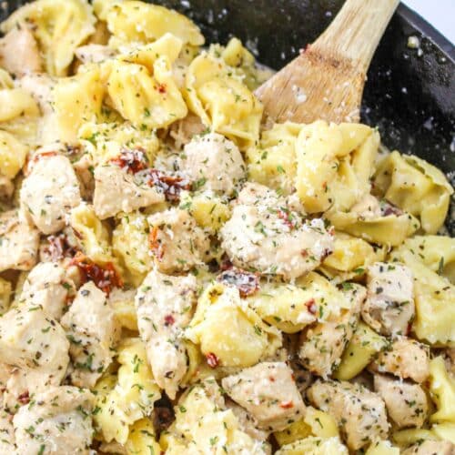 Marry Me Chicken Tortellini in a cast iron skillet with a wooden spoon sitting in the pan