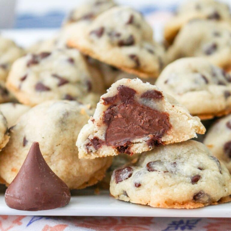 stack of chocolate chip hershey kiss cookies on a plate. with one of them cut in half.