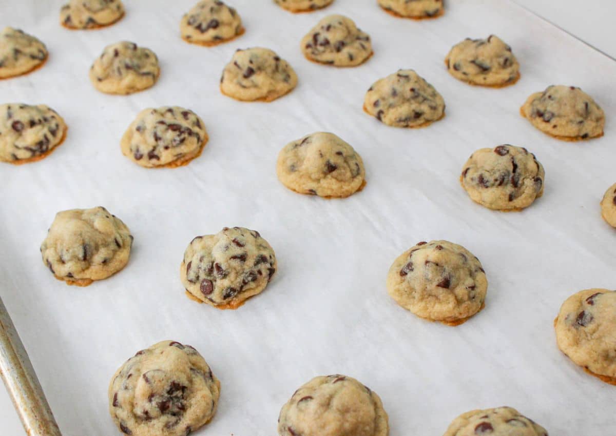 baked chocolate chip hershey kiss cookies on a parchment lined baking sheet.