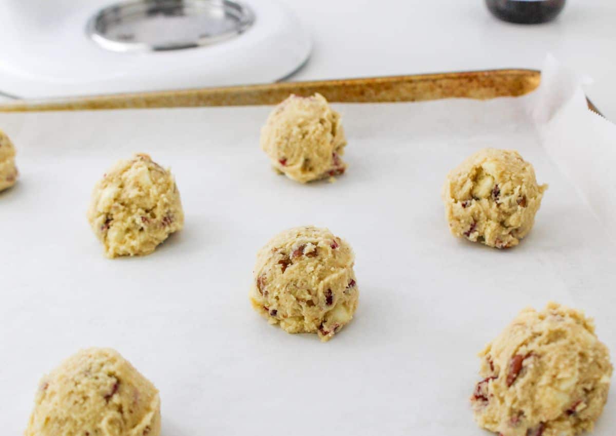 raw cookie dough balls on a parchment lined baking sheet.