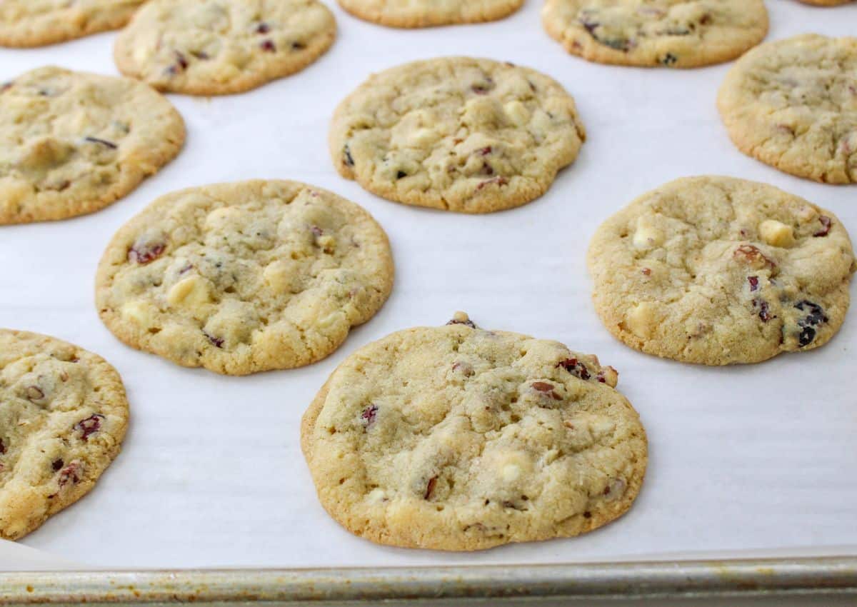 baked cranberry pecan cookies cooling on a parchment lined baking sheet.