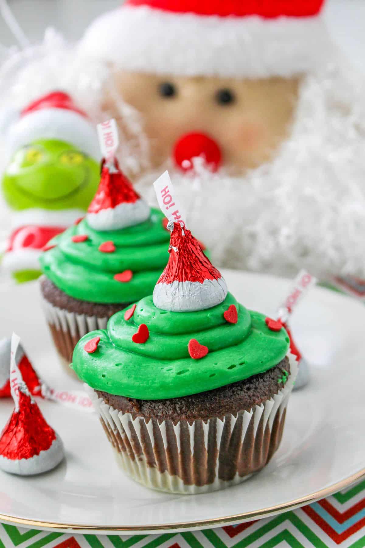two grinch cupcakes on a plate.