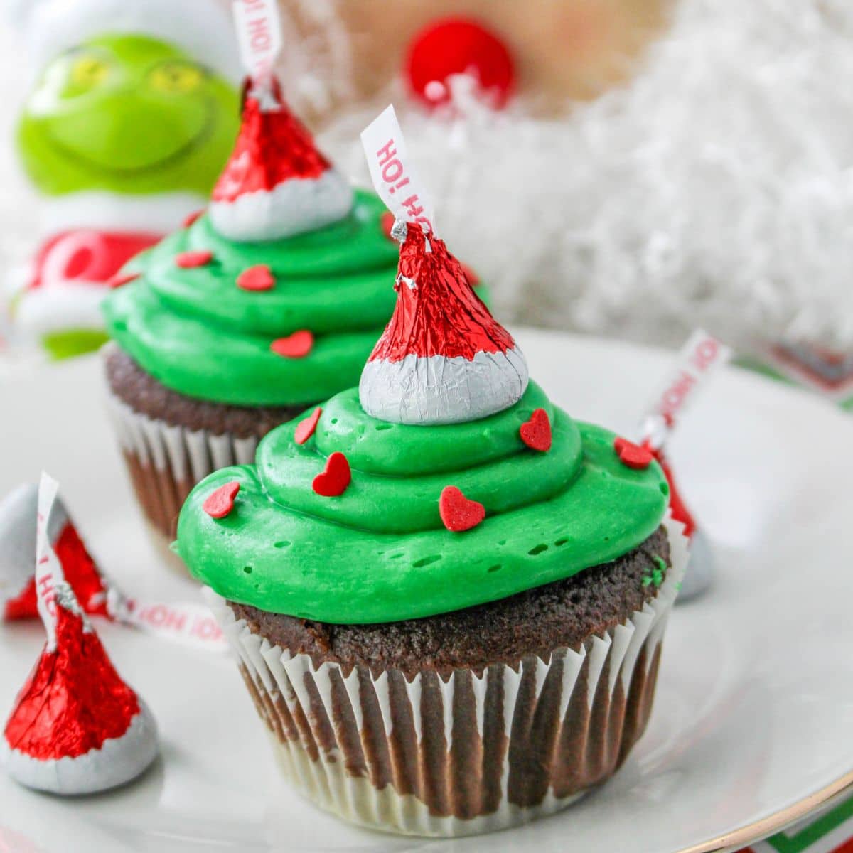 two grinch cupcakes on a plate.