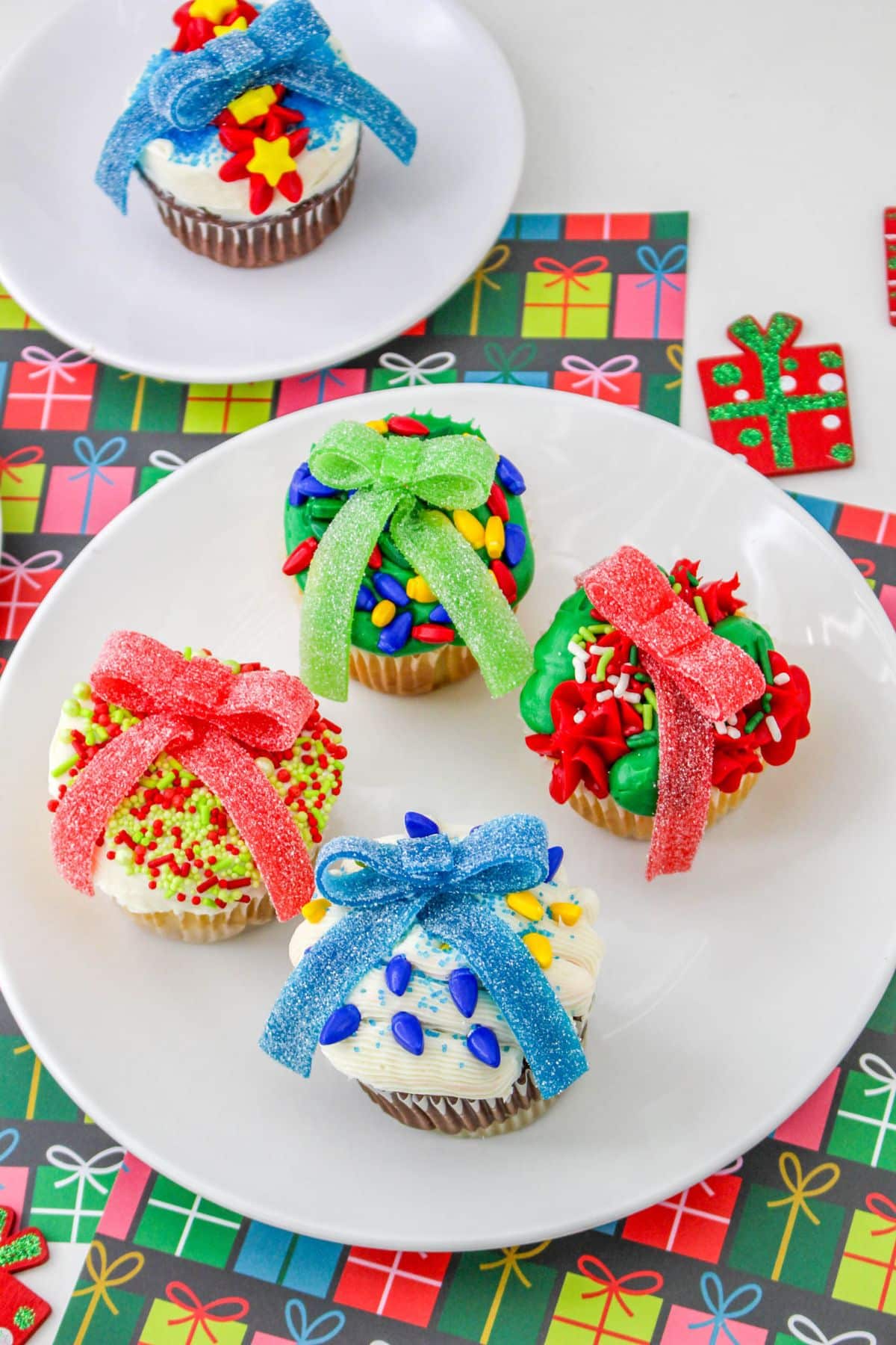 four ugly sweater cupcakes decorated in different colors on a plate.