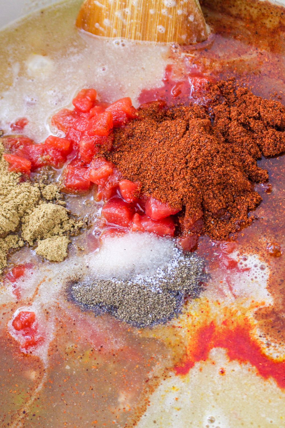 ingredient for turkey chili in a stockpot, and spices and seasonings on top of brth