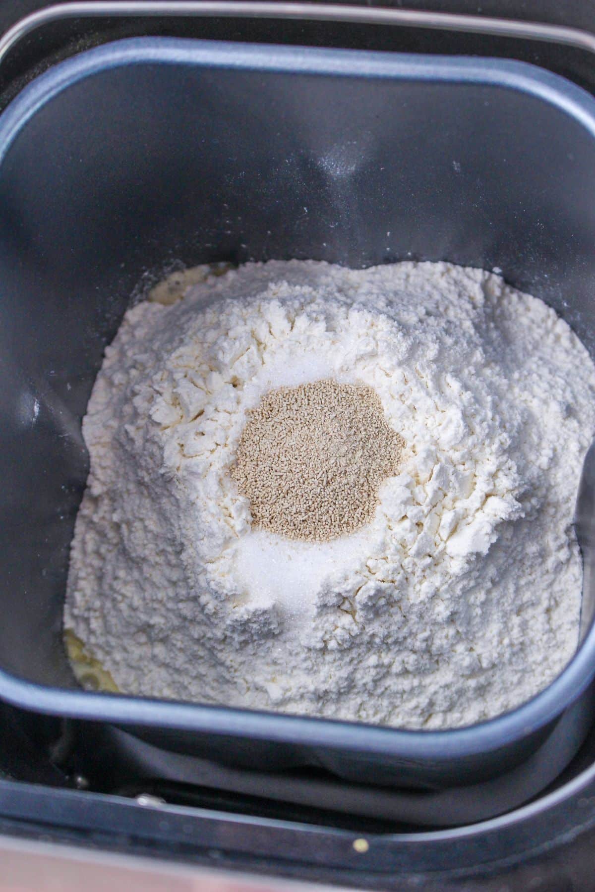 flour, salt, and yeast being added to the loaf pan.