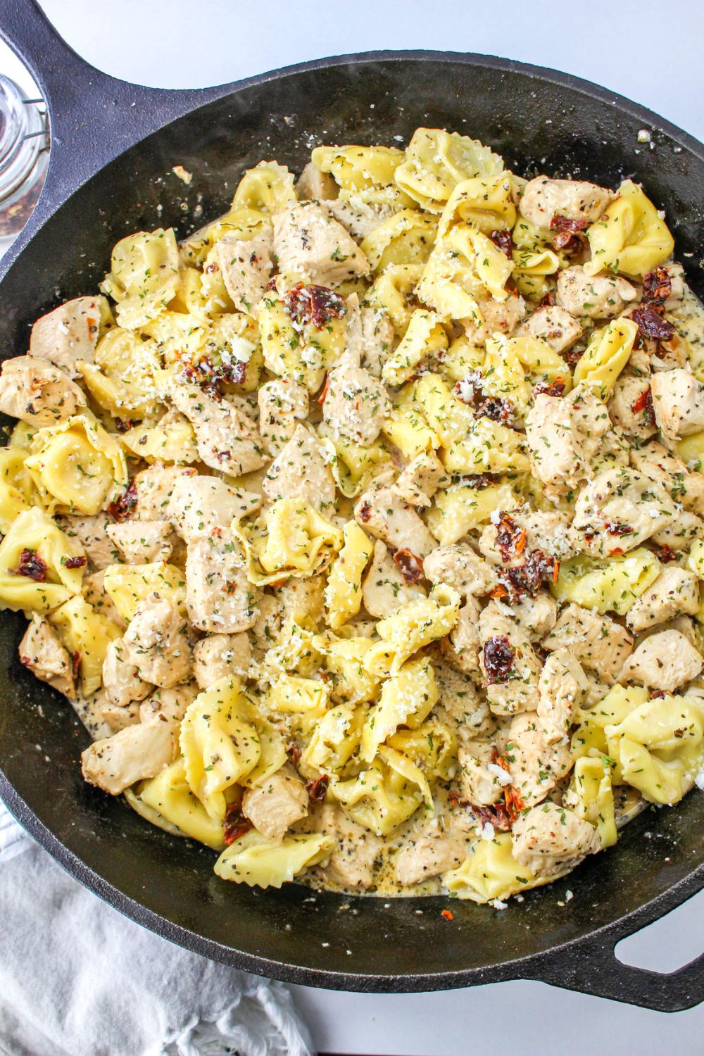 overhead shot of a chicken and tortellini pasta dish in a skillet sitting on table
