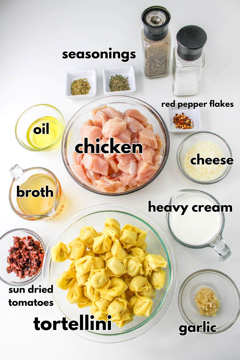 ingredients in individual bowls on table - chicken, tortellini, heavy cream, broth, sundried tomatoes, garlic, seasonings, and oil